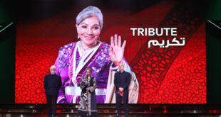 Par : AlArab-tv.com Marrakech – Le Festival international du film de Marrakech a rendu, mardi soir au Palais des congrès de la cité ocre, un hommage posthume émouvant à la grande dame du cinéma marocain, feue Naïma Elmcherqui, disparue en octobre dernier. Cette cérémonie, qui s’est déroulée en présence des membres de sa famille ainsi que d’éminentes personnalités du monde du cinéma, de l’art, de la culture et des médias, a été l’occasion de rendre un vibrant hommage à la mémoire d’une femme engagée, une icône de la scène artistique nationale, ayant marqué son époque par des œuvres d’une qualité exceptionnelle. A cette occasion, la fille de feue Naïma Elmcherqui, Yasmine Khayat a exprimé, au nom de sa famille, sa profonde gratitude à SM le Roi Mohammed VI et ses vifs remerciements à SAR le Prince Moulay Rachid, Président de la Fondation du Festival international du film de Marrakech. Yasmine Khayat, qui a reçu l’Étoile d’or du Festival des mains de l’artiste Fatima Khair, a salué l’initiative du Festival de rendre hommage à sa défunte mère, qui était “une femme singulière, amoureuse du cinéma”, reconnue pour ses initiatives et ses rôles humanitaires en faveur des femmes et des enfants.